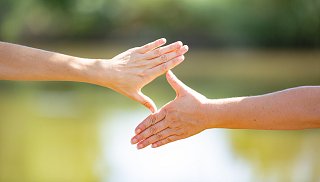 Zwei Hände formen eine Raute