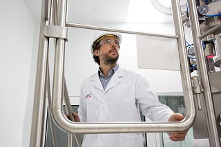 Mann mit Schutzkleidung auf Treppe vor technischer Anlage