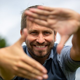 Mann formt Raute mit seinen Händen